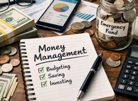 Money management concept showing a realistic financial planning workspace with notebook labeled budgeting, saving, and investing, cash stacks, calculator, smartphone with charts, and an emergency fund jar representing personal finance organization and wealth planning.