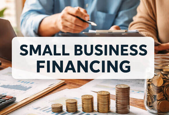 Close-up of two individuals reviewing financial charts and documents at a desk. In the foreground, stacks of coins are arranged, symbolizing small business financing. The title 'SMALL BUSINESS FINANCING' is prominently displayed across the top in bold blue text.